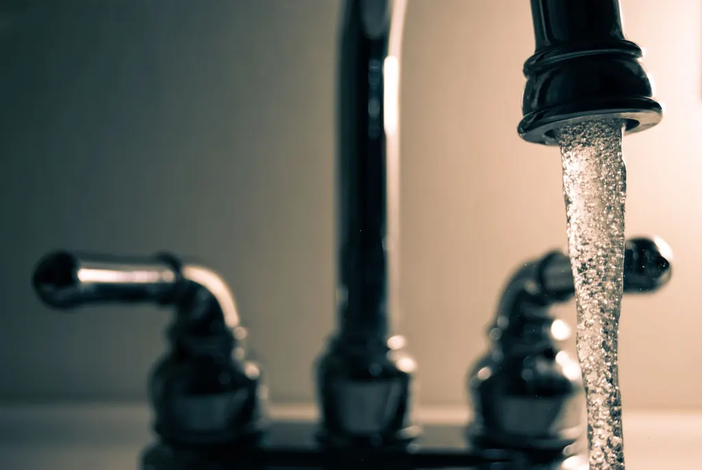 Clear water flowing from a steel faucet — recommended for Ballantrae hard water treatment